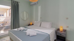 A hotel room with a bed, two bedside tables with lamps, a round mirror, and a balcony view.
