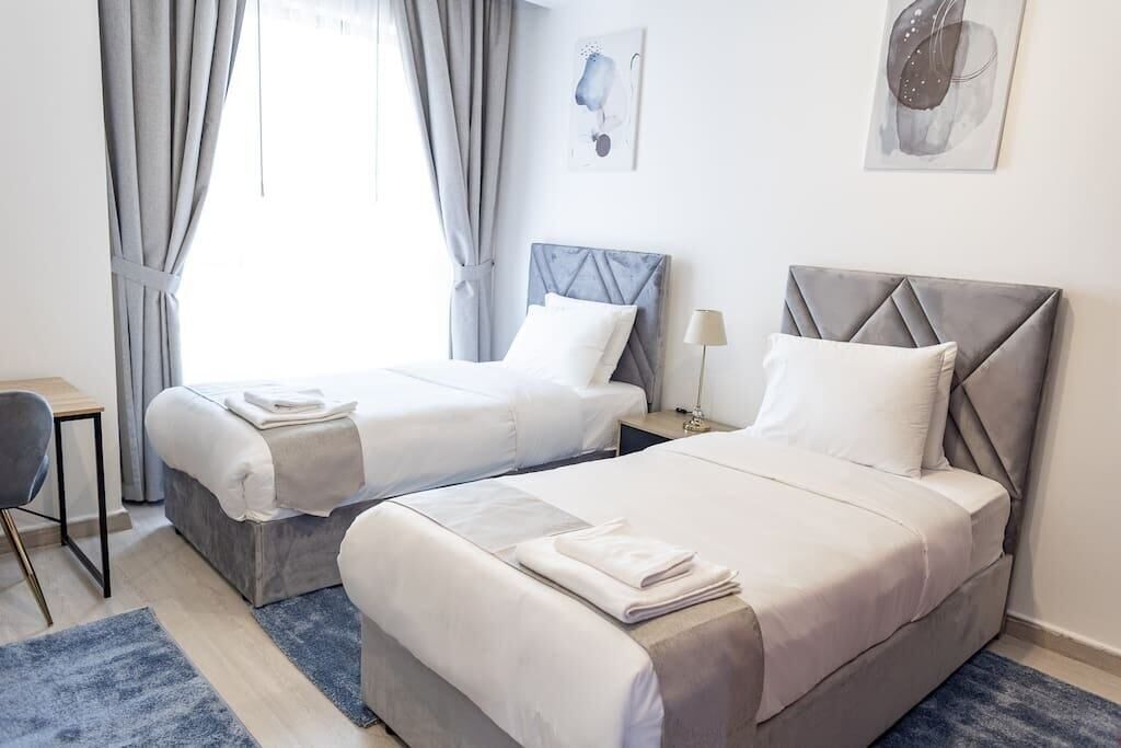 A hotel room with two beds, a desk, and a chair.