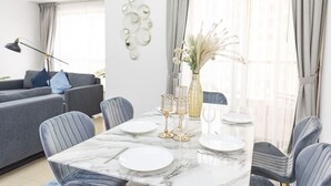 A dining area with a marble table set for four, surrounded by grey upholstered chairs.