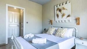 A neatly arranged bedroom with a bed, bedside tables, and a door. - Skopelos Seaview Suite - Demeter Summer Nest (Stafylos)