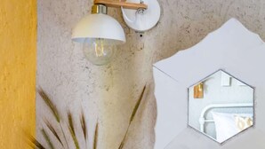 A room with a bed, a wall-mounted mirror, and a lamp. - Skopelos Seaview Suite - Demeter Summer Nest (Stafylos)