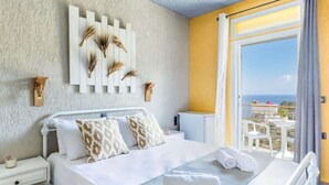 A bedroom with a bed, bedside tables, a wall-mounted artwork, and a balcony with a view. - Skopelos Seaview Suite - Demeter Summer Nest (Stafylos)