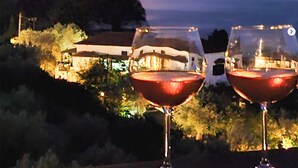 Two wine glasses on a table with a view of a coastal landscape at dusk. - Skopelos Seaview Suite - Demeter Summer Nest (Stafylos)