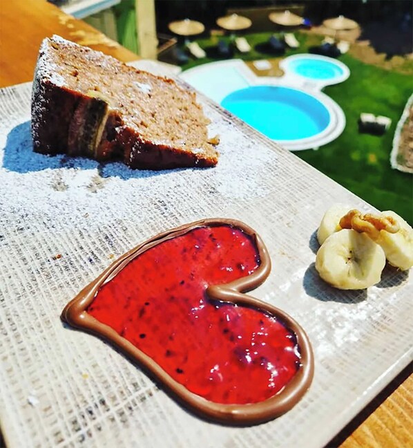 A dessert plate with a slice of cake, a heart-shaped jam, and banana slices.