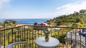 A balcony with a view of the sea, a small table with a potted plant, and outdoor seating. - Skopelos Seaview Suite - Hebe Summer Nest (Stafylos)