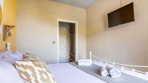 A hotel room with a bed, a TV mounted on the wall, and a door leading to a closet. - Skopelos Seaview Suite - Hebe Summer Nest (Stafylos)