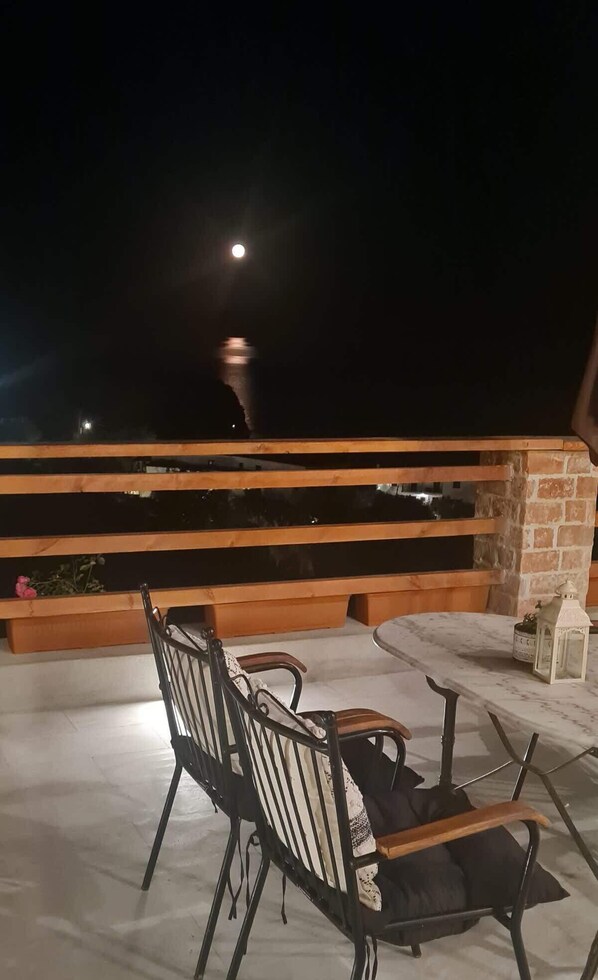 An outdoor seating area with a wooden railing, a table, and two chairs. - Skopelos Seaview Suite - Persephone Summer Nest (Stafylos)