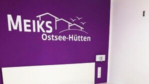 Un lit avec une literie blanche, un mur violet orné d’un logo et une table de chevet blanche.