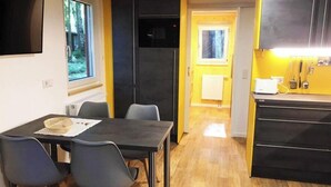 Une cuisine de taille réduite avec un coin repas, un plancher en bois et une vue sur l’extérieur par une fenêtre.