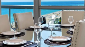 Mesa de comedor dispuesta para seis personas con vista al océano y a la playa.