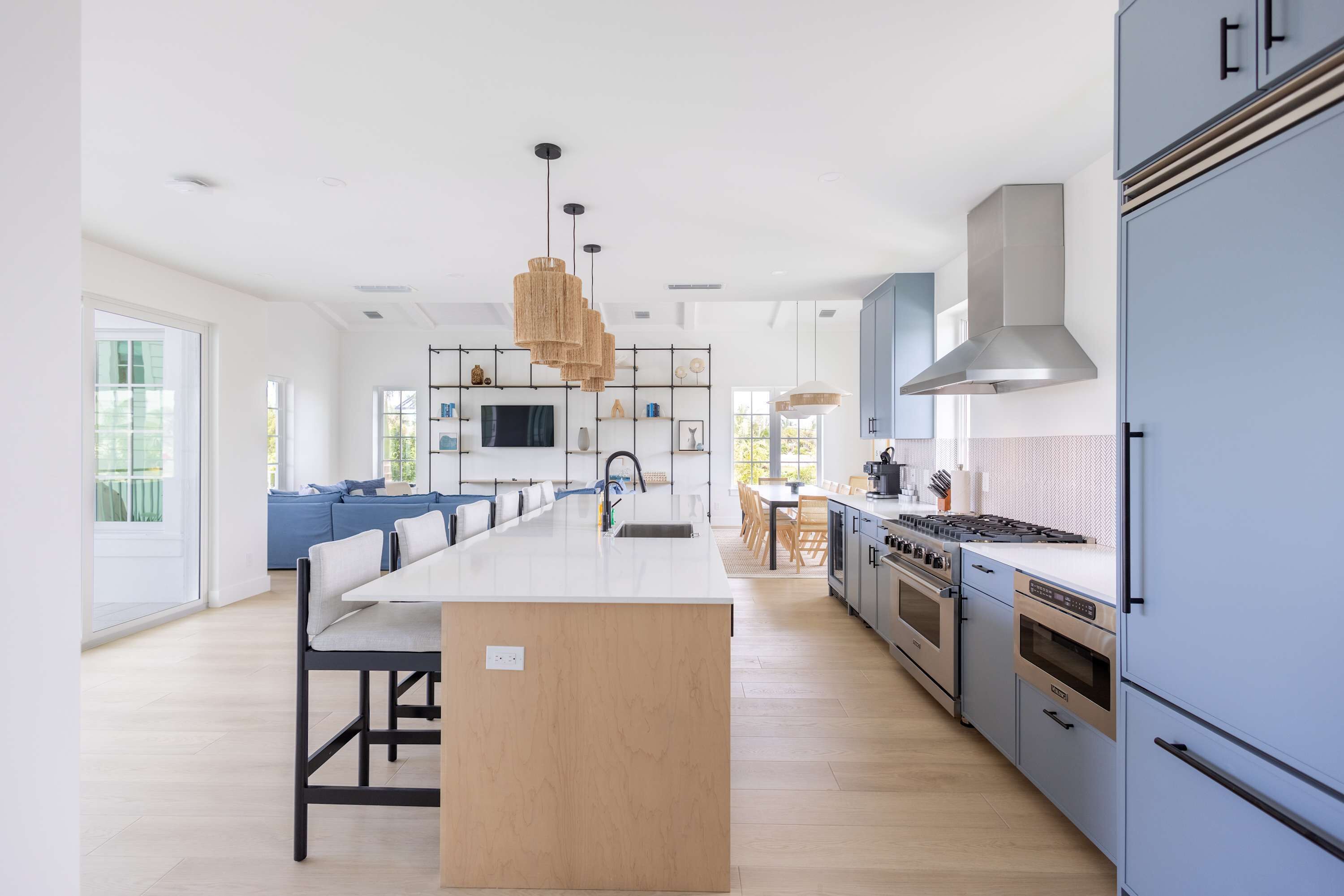 Una cocina moderna con una isla central, electrodomésticos integrados e iluminación colgante.