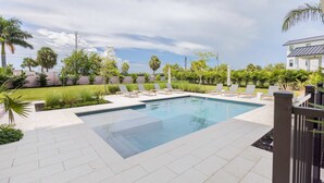 A rectangular swimming pool with a tiled deck, surrounded by lounge chairs and palm trees. - Palmgale Estate at Lunara Bay (Key West)