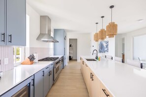 A modern kitchen with a central island, stainless steel appliances, and pendant lighting. - Palmgale Estate at Lunara Bay (Key West)
