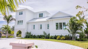 A two-story white house with a covered patio area. - Palmgale Estate at Lunara Bay (Key West)