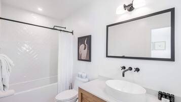 Une salle de bain moderne équipée d’une douche, de toilettes, d’un lavabo et d’un grand miroir.