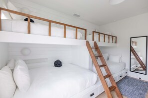 A bunk bed with a wooden ladder, white bedding, and a small round light fixture on the wall. - Palmgale Estate at Lunara Bay (Key West)