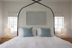 A neatly made bed with white bedding and two pillows, a bedside table with a lamp, and a window with a view. - Floralee House at Lunara Bay (Key West)