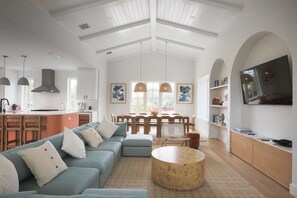 A spacious living area with a large sofa, a round coffee table, and a dining set.