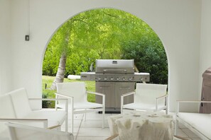 An outdoor seating area with white chairs and a barbecue grill. - Floralee House at Lunara Bay (Key West)