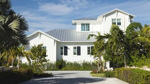A modern two-story house with a grey roof, white exterior walls, and a paved driveway.
