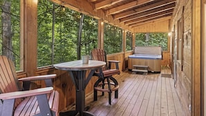 Una terraza de madera con un jacuzzi, sillas de madera y una mesa.