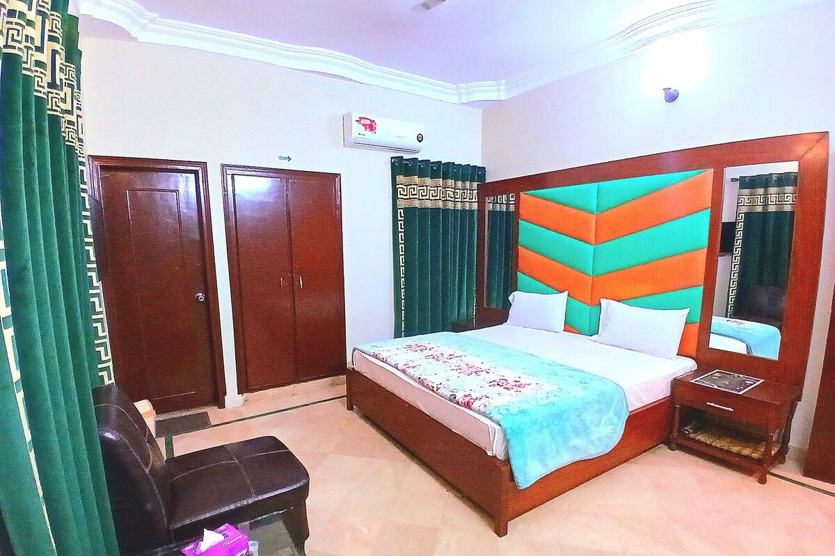 Un dormitorio con cama, armario, mesita de noche y una pequeña mesa con silla.