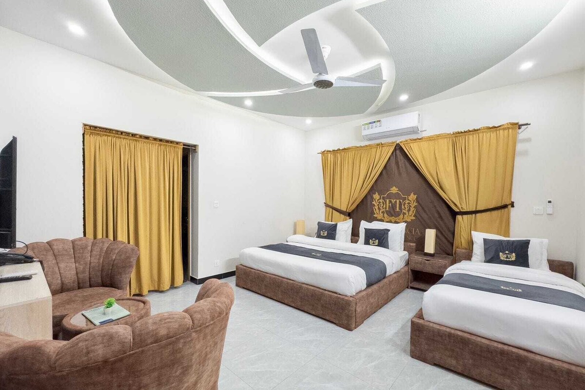 Une chambre d’hôtel avec deux lits, un canapé, une télévision et un appareil de climatisation.