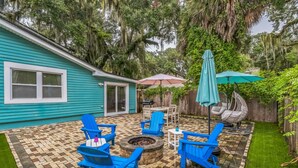 A backyard patio with blue Adirondack chairs, a fire pit, and a table with an umbrella. - Relaxing Home Near St. Augustine Attractions 4 Bedroom Residence (St. Augustine)