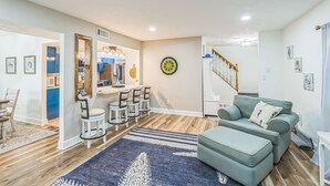 A modern living room with a sofa, a dining area with chairs, a kitchen in the background, and a staircase leading upstairs. - Relaxing Home Near St. Augustine Attractions 4 Bedroom Residence (St. Augustine)
