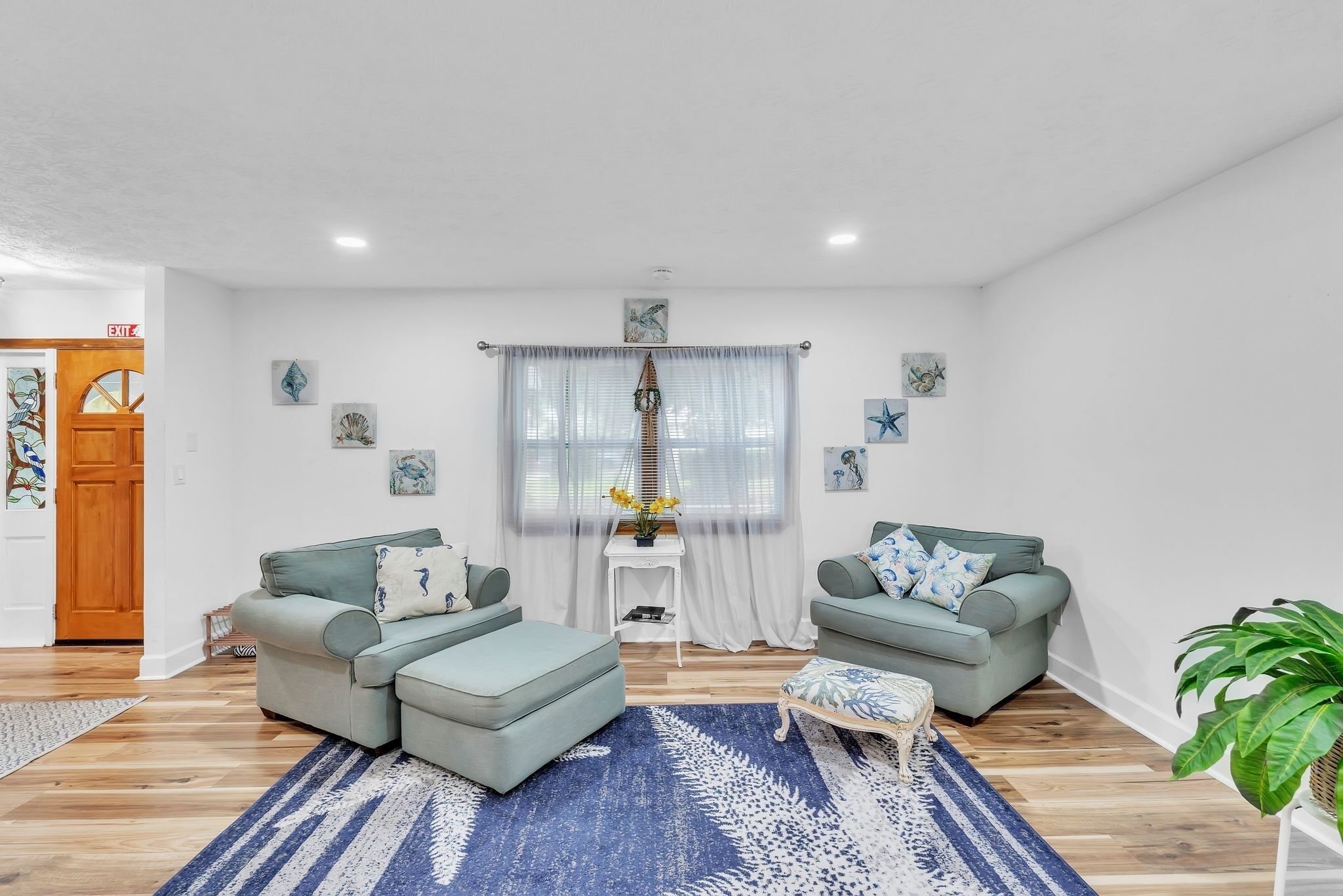 A living room with two grey sofas, a blue patterned rug, and a small white side table with a vase of flowers.