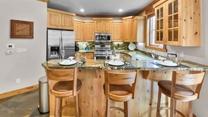 A kitchen with wooden cabinets, a stainless steel refrigerator, a microwave, and a granite countertop.