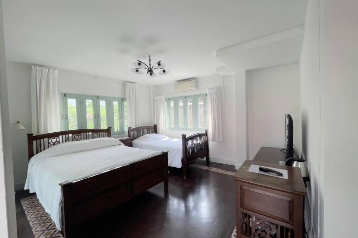 Een slaapkamer met een houten bed, twee nachtkastjes, een bureau en een stoel.