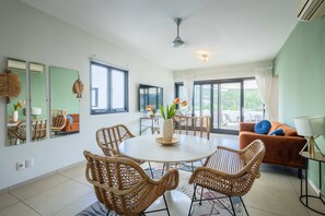 A dining area with wicker chairs, a round table, and a vase with flowers. - Seabreeze Retreat Stylish Blue Bay Residence (Sint Michiel)