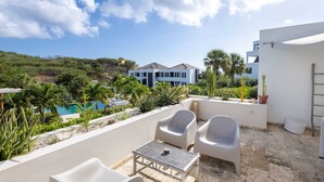 Una terraza con mobiliario exterior, piscina y vistas a un edificio moderno.