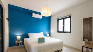 Un dormitorio con cama, lámparas de noche, una ventana y un escritorio.