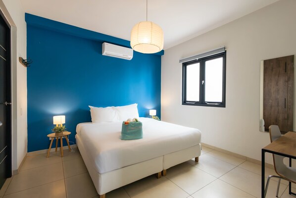 Une chambre à coucher avec un lit, des lampes de chevet, une fenêtre et un bureau.