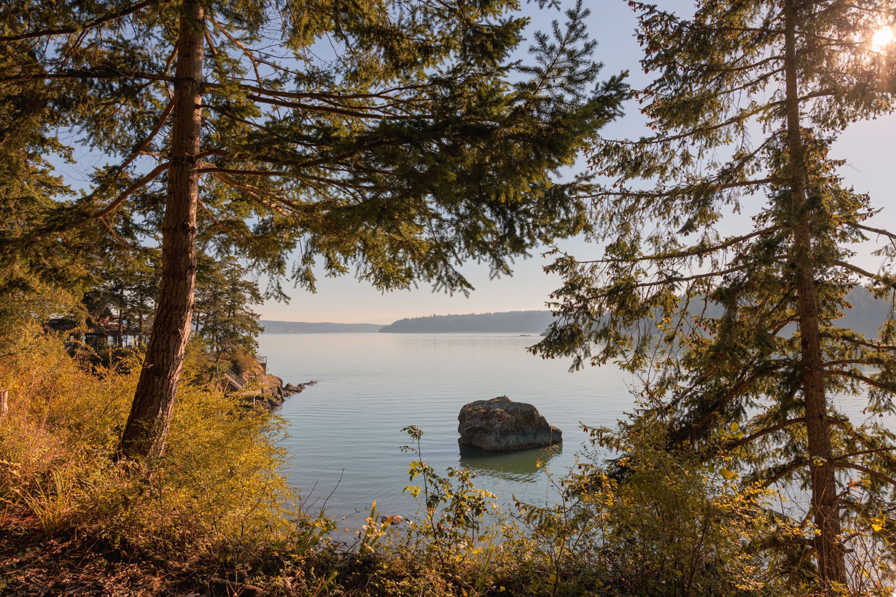 Un lac paisible, entouré d’une forêt dense et bordé d’une formation rocheuse imposante.
