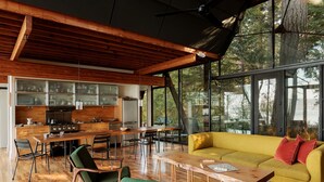 Una cocina moderna con armarios de madera y un comedor con un sofá amarillo y sillas verdes.