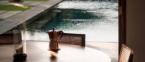A round table with chairs, a coffee pot, and a glass of water.