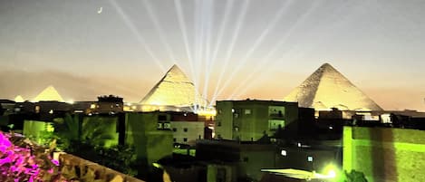 Une vue des pyramides au coucher du soleil, avec des bâtiments au premier plan.