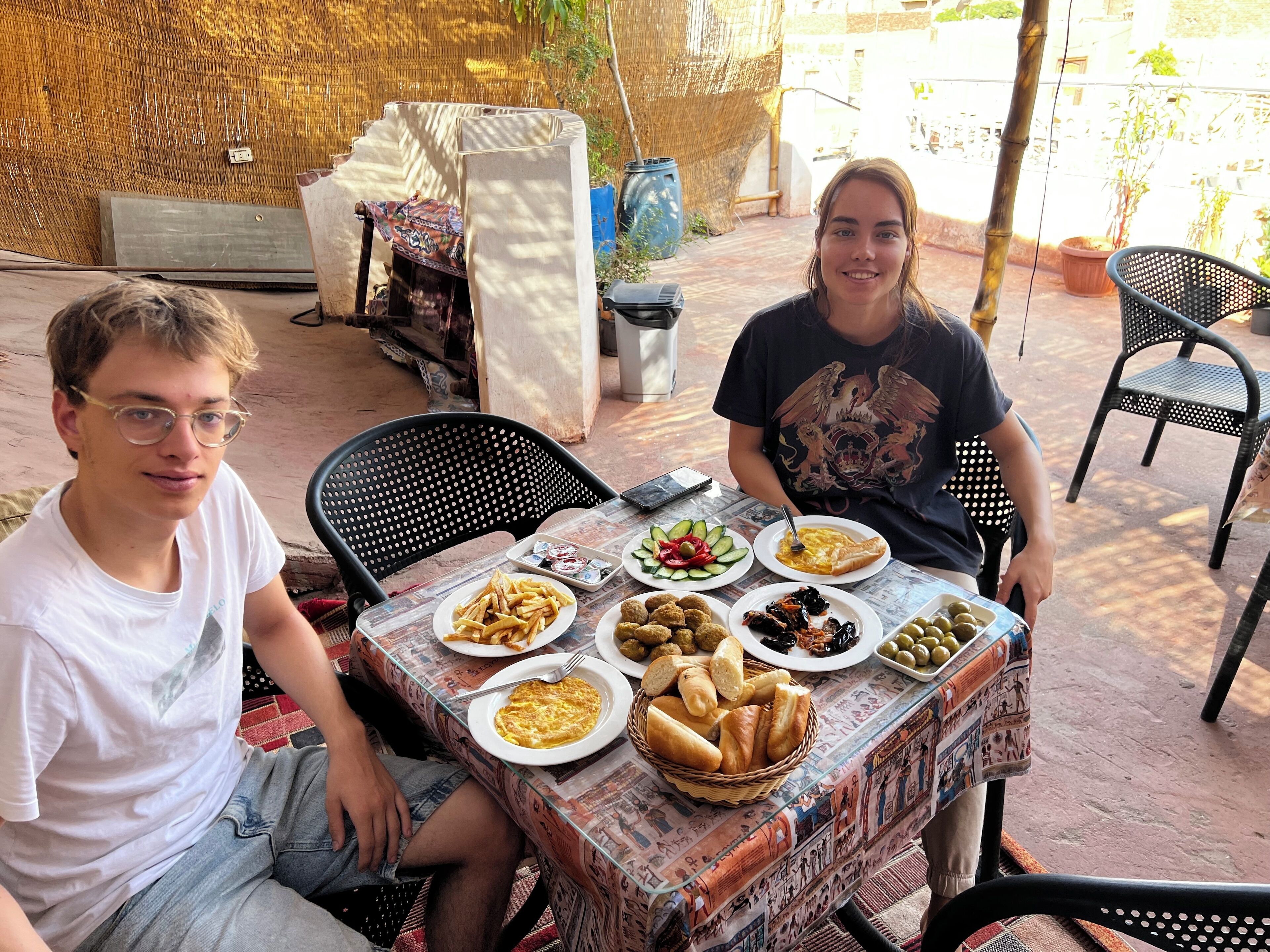 Two people seated at a table with various dishes, including bread, salad, and meat.