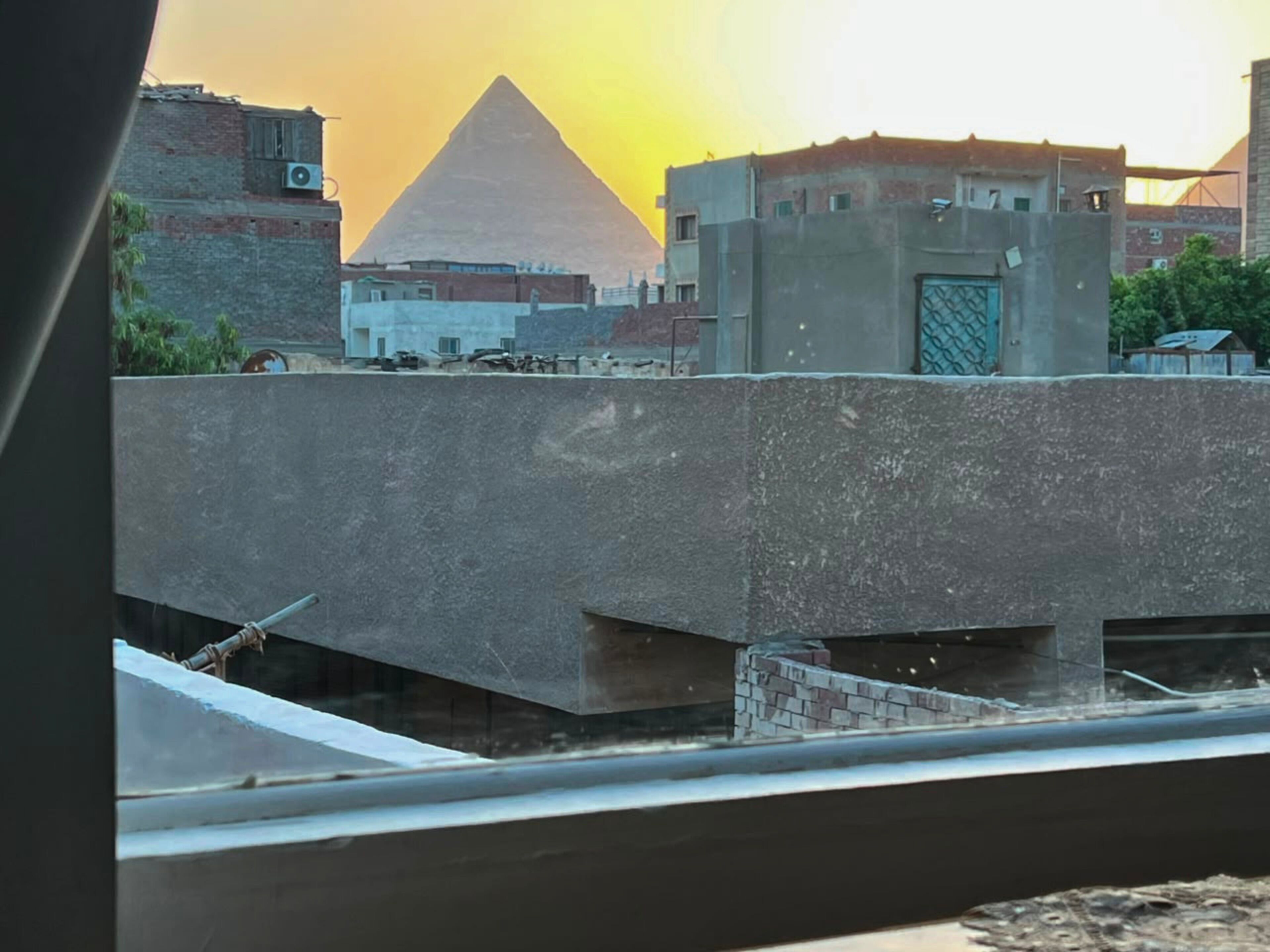 A pyramid in the background with a building in the foreground.