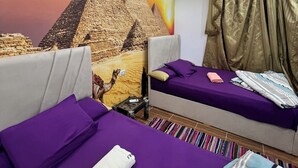 A hotel room with two beds, purple bedding, a mural of pyramids, and a curtain. - Jana pyramids view inn (Giza)