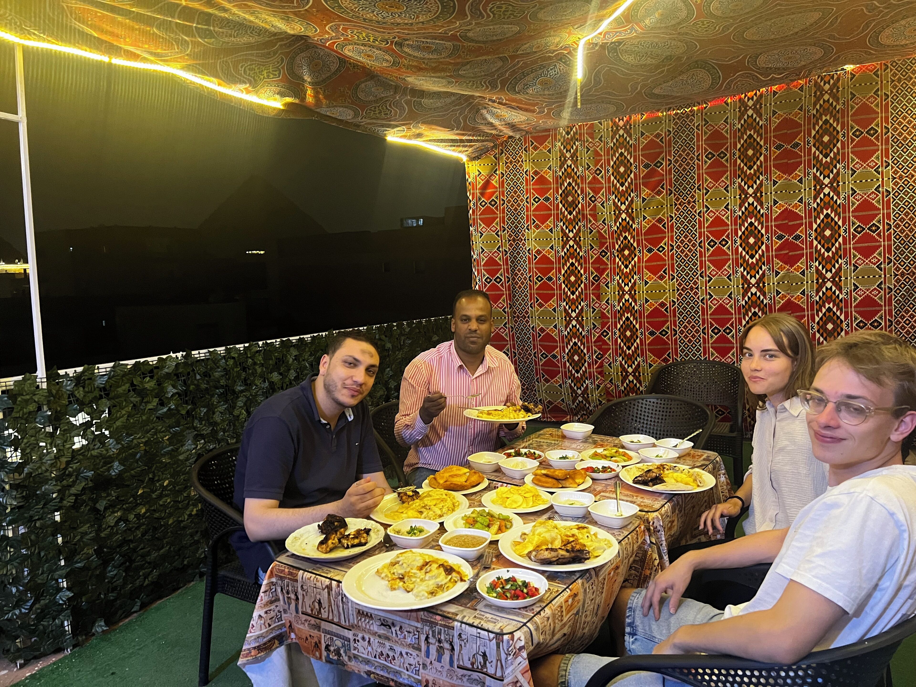 A dining area with a table set for a meal, surrounded by patterned walls and a decorative ceiling.