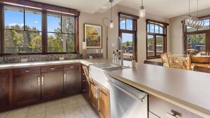 A modern kitchen with large windows, a central island, and wooden cabinetry.