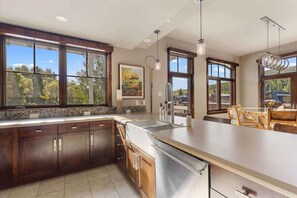 A modern kitchen with large windows, a central island, and wooden cabinetry.