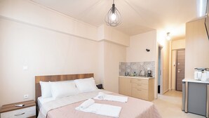 A bedroom with a bed, bedside tables, a nightstand, a desk, and a kitchenette. - Monastiraki metro st studio for 2 persons by MPS (Athina)