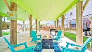 Un espace extérieur aménagé, abrité et doté de chaises de couleur turquoise et d’un foyer central.