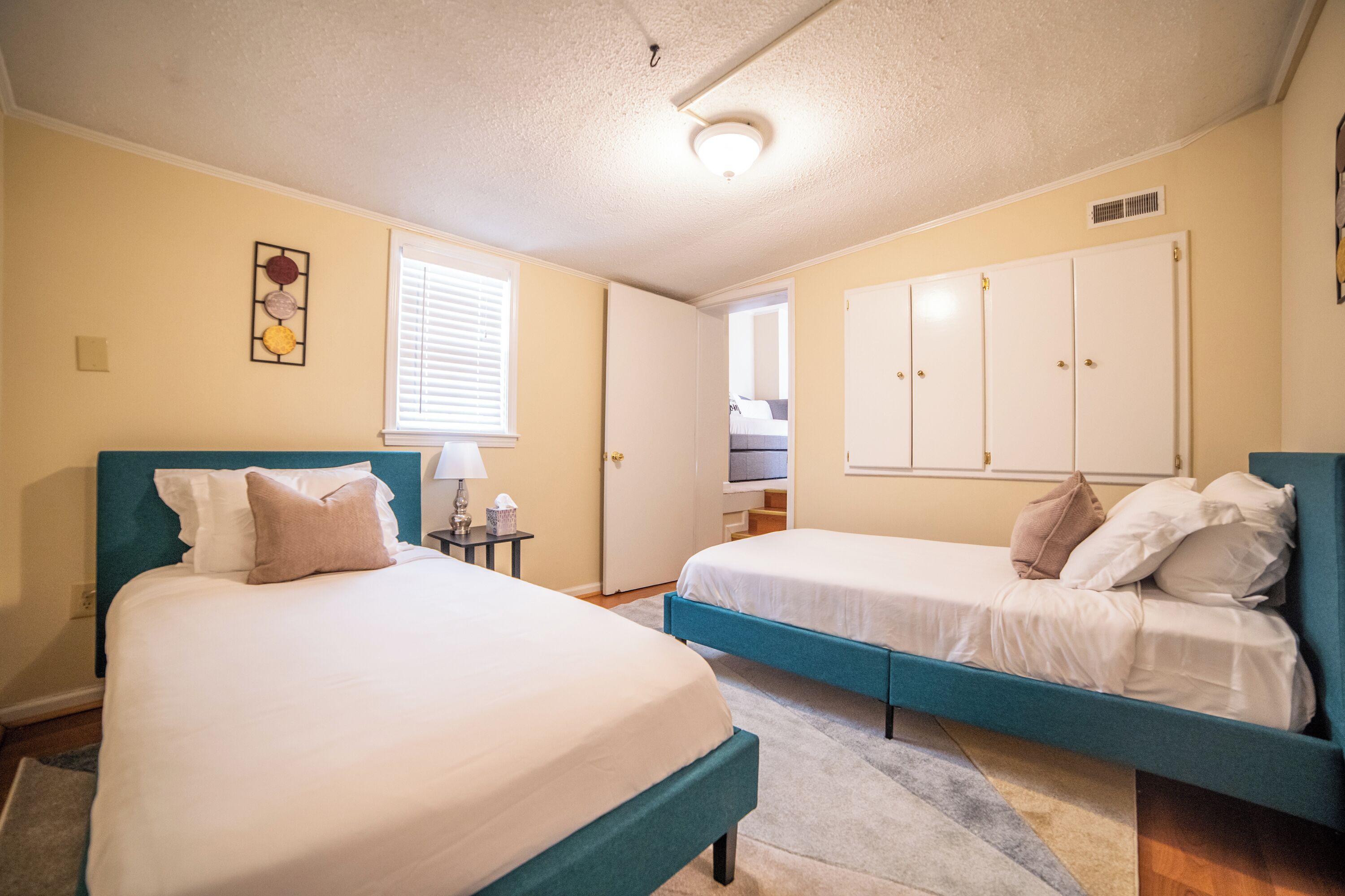 A bedroom with two beds, a window, a ceiling light, and a wardrobe.