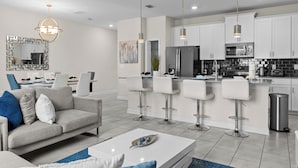 A modern kitchen with white cabinets, stainless steel appliances, and a central island with bar stools. - Modern 4BR Pool Townhome | Pet-Friendly 361 (Kissimmee)
